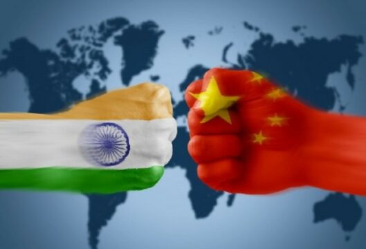 Fist painted with Indian flag opposite fist painted with China flag with world map in background